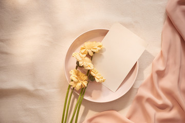 Flowers on plate with card and fabric on the light background