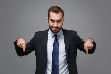 Confident young bearded business man in classic black suit shirt tie posing isolated on grey wall...