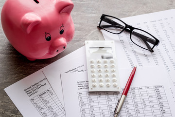 Taxes calculation concept. Financial documents, piggy bank, calculator on dark wooden background