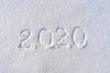 Text 2020 written on white fresh snow in sunny winter day. Merry Christmas and Happy New Year. Winter holiday concept