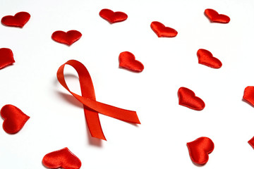 Red ribbon as symbol of aids awareness with red hearts on white background.