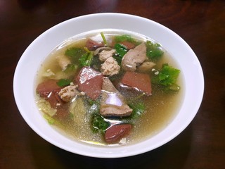 Thai food style, Top view of clear soup with pork, congealed pork blood, lvy gourd sprinkled in white bowl isolated on black background, Ready to eat or serve