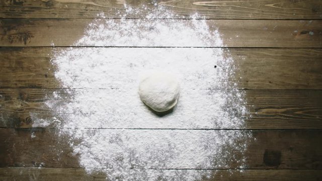 woman throws dough onto kitchen table upper view slow motion