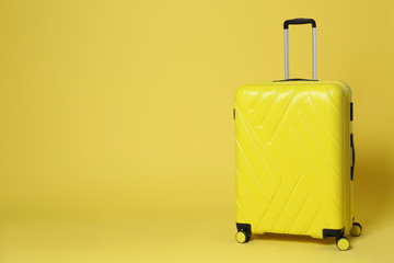 Stylish suitcase on yellow background. Space for text