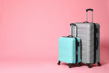Stylish grey and turquoise suitcases on pink background. Space for text