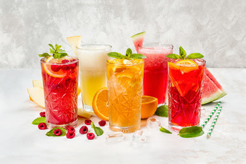 Different lemonades in glasses of fruits on the background