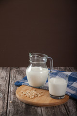 Vegetarian pine nut milk in a glass cup and jug, on a wooden stand with a blue linen napkin.