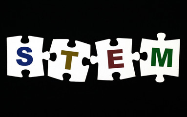 Four pieces of puzzle with letters STEM on black background.