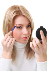 Beautiful blond woman applying eyebrow pencil