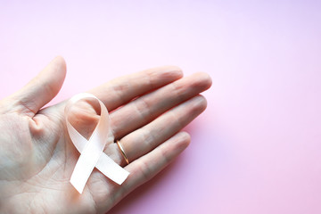 Womans hand holding Pink Ribbon for supporting people living and illness. Healthcare, International Women day and World cancer day concept.