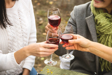 Women at Family Autumn Lunch clinks with wine glasses for a family holiday autumn dinner in the backyard.