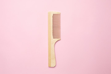 Eco wooden comb on pink background , bathroom and hair accessory