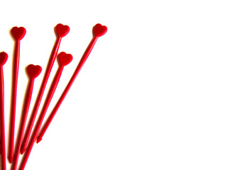 Red plastic sticks for canapes with a heart on a white isolated background. Decorative chopsticks.
