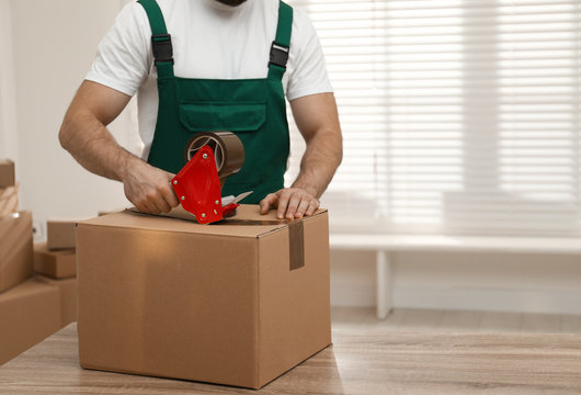 Man Packing Box With Adhesive Tape Indoors, Closeup. Moving Service