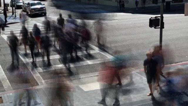 Crowded pedestrians crossing the street crosswalk with driving cars