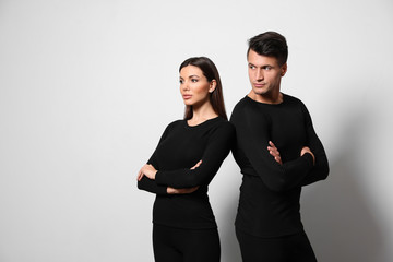 Couple wearing thermal underwear on light grey background. Space for text