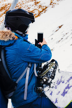 girl snowboarder takes pictures with smartphone.