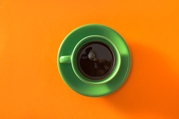 Green cup of coffee on orange background