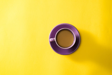 Purple cup of coffee on the yellow background