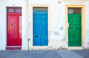 Fototapeta na wymiar Three typical traditional maltese doors in Marsaxlokk village. Red, blue, green doors. Morning. Malta country