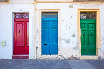 Three typical traditional maltese doors in Marsaxlokk village. Red, blue, green doors. Malta