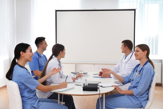 Team of doctors using video projector during conference indoors