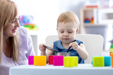 Obraz na płótnie Canvas Baby toddler with mom play in nursery