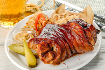 Knuckle on a white plate, next to a light beer