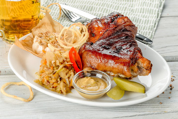 Knuckle on a white plate, next to a light beer