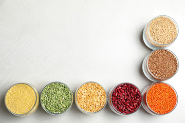 Jars with different cereals on white background, flat lay. Space for text
