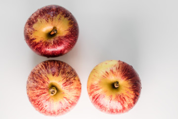 Fresh red yellow striped apples with water droplets on a white glossy kitchen table. Tasty bright juicy fruits. Healthy eating Isolated object	