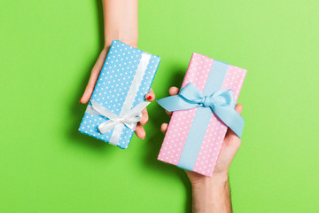 Top view of a woman and a man exchanging gifts on colorful background. Couple give presents to each other. Close up of making surprise for holiday concept