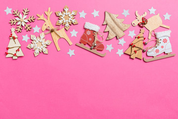 Top view of pink background decorated with festive toys and Christmas symbols reindeers and New Year trees. Holiday concept with copy space