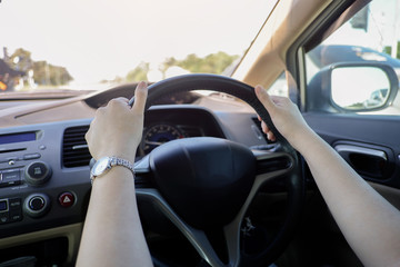 Female hands on the steering wheel of a car. Woman hands holding a steering wheel confidently.