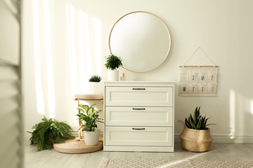 Stylish room interior with chest of drawers and round mirror