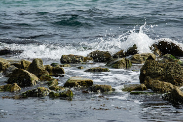 Breathtaking sea of ​​traditional emerald color. Foamed sea waves break on stones near shore. Blue, green and emerald colors are perfect backdrop forrelaxing theme. Elegant nature concept for design.