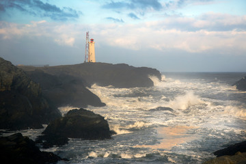 Fototapeta premium light house on the cliff with the wild sea wave in Iceland