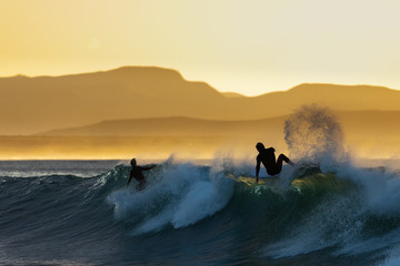 Surfers having fun at sunrise at Super Tubes in Jeffreys Bay, South Africa