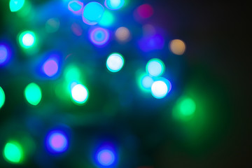 Abstract Christmas background. Photo of glowing blurry lights. Decoration garland with multi-colored flickering lights