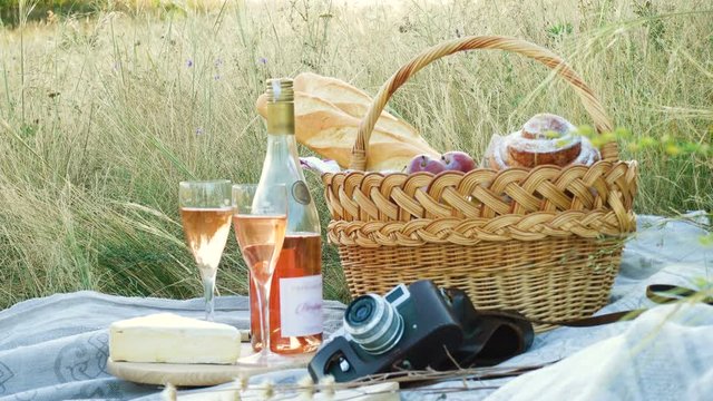 picnic basket with the food and bottle of wine on a grass at the field