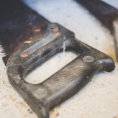 Plastic black handle old saw on a stone floor, close-up.