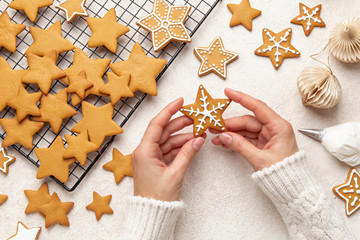 Close up of female hands decorating Christmas  gingerbread cookies