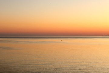 Orange and red sunset colors in the sky and in the calm smooth water