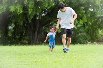 Obraz premium Asian father and daughter are running together on the green field with full of happiness moment, concept of love and relation in family life, selective focus photograph.