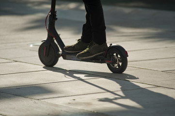 electric scooter with dark sport shoes and black pants