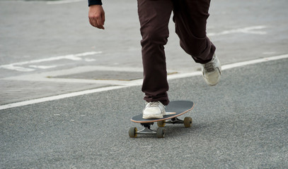 boy skating in cobblestone street brown pants