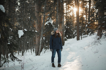 Beautiful smiling young woman walking in winter forest. Winter concept