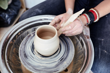 Fototapeta na wymiar Woman's hands molding clay. Potter making ceramic pot in pottery workshop
