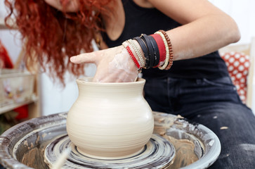 Fototapeta na wymiar Woman's hands molding clay. Potter making ceramic pot in pottery workshop