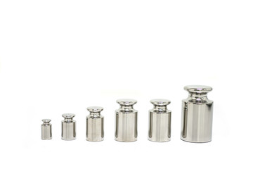 Stainless steel weights for balance calibration, isolated white background.